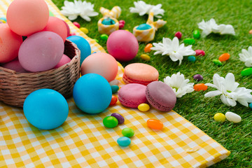 Easter composition with colored eggs and bright candies on yellow tablecloth