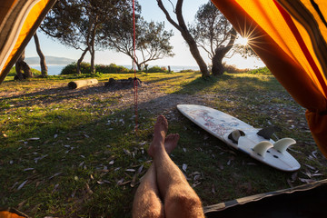 Point of view from a tent of man relaxing during crisp morning on a surf hike in Australia