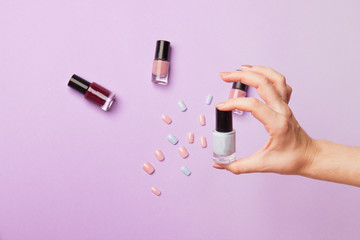 woman hand with manicure show OK and bottle with nail polish on purple backround