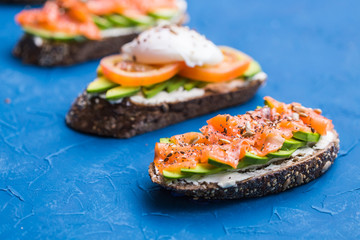 Sandwiches with smoked salmon and avocado on blue background. Concept for healthy nutrition.