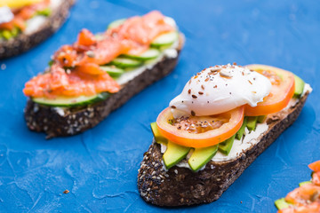 Sandwiches with smoked salmon and avocado on blue background. Concept for healthy nutrition.