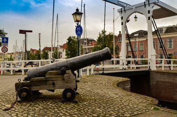 Goes, the Netherlands, August 2019. The port in the historic center, an ancient cannon remained to guard the entrance. His mouth points threateningly towards the incoming boats.