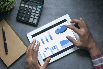 top view of man hand analyzing chart on digital tablet.
