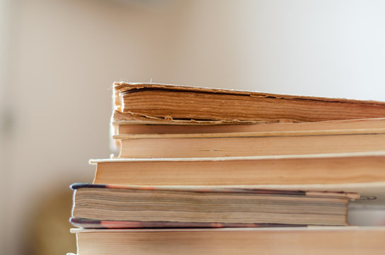 A stack of old books on a desk in a library. Side view of 6 battered textbooks. Free space for text. Close-up. Selective focus. Landscape photo arrangement.