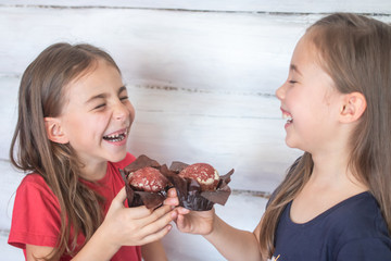 Kids laughing and eating chocolate muffins at a birthday party.