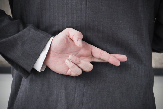 Businessman with his fingers crossed behind his back.Dishonest relationship and betrayal concept