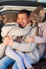 Fototapeta premium dad and daughters sitting in the trunk of a car 