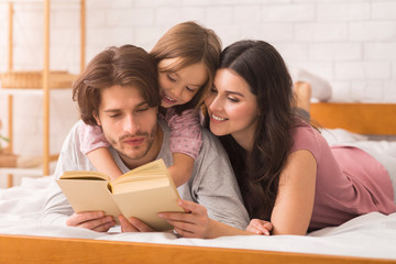 Loving Parents Reading Fairy Tale Book To Their Little Daughter