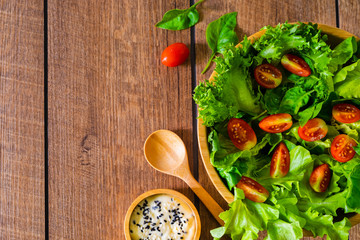 Fresh green vegetable salad. above of cherry tomato, onion, spinach and lettuce in wooden bowl with spoon, salad sesame dressing. Home made, Diet food for tasty and healthy meal. Top view, copy space.