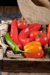 Red and green chilies with tomatoes in the wooden container.