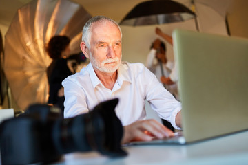 &Auml;lterer Fotograf am Laptop Computer  im Fotostudio