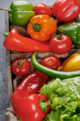 Peppers, tomatoes and greenery in a wooden container. Top view.