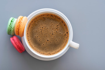Top view of coffee cup, macarons, envelope on gray background. Morning, breakfast holiday concept.