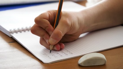 child writing in a notebook, math homework assignment - Powered by Adobe