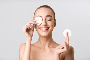 Young Woman Posing With Cotton Pads Covering Eye, Gray Background