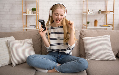 Pretty blonde girl playing video games at home