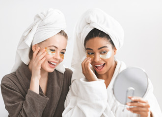 Impressed girlfriends with eye patches on looking at mirror