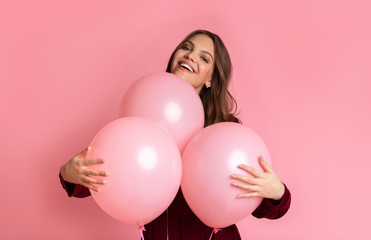 Playful Young Girl Cuddling Three Balloons And Sincerely Smiling