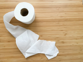 A row of white toilet paper with paper roll out and place on wooden background. Close up, top view selective focus with copy space.
