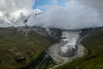 Dramatic autumn landscape with glacier Lardaad Adishi and mountain Tetnuldi hiding in clouds in Svaneti Georgia big kar and small tongue because of global warming