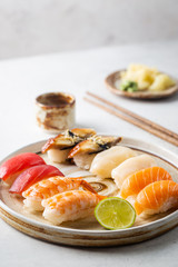 Set of sushi and maki on plate with soy sauce and chopsticks on white background. Top view with...