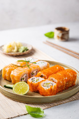 Set of sushi and maki on plate with soy sauce and chopsticks on white background. Top view with...