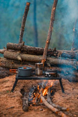 Primitive Bushcraft survival debris hut with campfire ring outside. Blanket, shelter, fire in the forest.