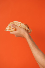 Mexican national food taco or Tatar national food kystyby in hand on an orange background.Food in a tortilla.National food concept