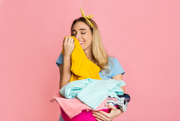 Young woman Smelling Clean Clothes and smiling
