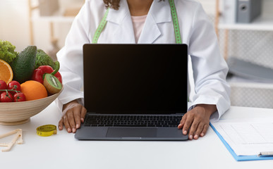 Nutritionist's workplace in clinic with blank laptop screen