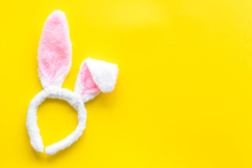 Easter bunny concept. Toy rabbit's ears for head on yellow background top-down copy space