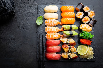 Set of sushi and maki with soy sauce over black background. Top view with copy space