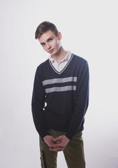 Fototapeta premium Lifestyle photo of a young brown-haired man on a light background, a beautiful young guy in a shirt and sweater