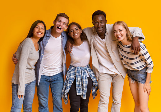 Friendly group of international students smiling over yellow background