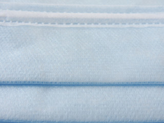 Naklejka premium Close up of a blue disposable surgical mask. Novel coronavirus (COVID-19). Health and medical concept. Face mask background. Non-woven fabric.