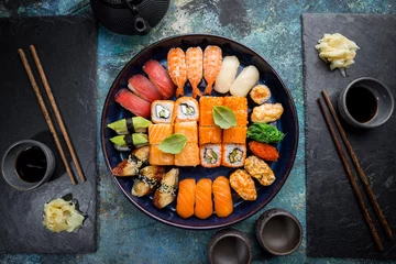 Fotobehang Set of sushi and maki with soy sauce over blue stone background. Top view with copy space © petrrgoskov
