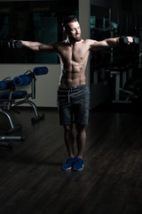 Fototapeta na wymiar Bodybuilder Exercising Shoulders With Dumbbells