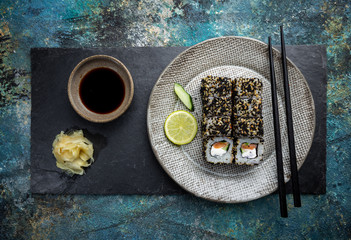 Set of sushi and maki with soy sauce over blue stone background. Top view with copy space