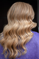 Naklejka premium Long hair of a blonde woman with wave hairstyle