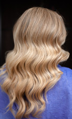 Naklejka premium Long hair of a blonde woman with wave hairstyle