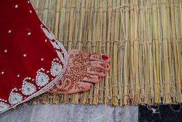 Indian traditional wedding. authentic Vedic wedding ritual called vivaha Yajna. Red Sari, women foot with mehendi close-up. garlands of flowers. Sacred fire ritual. multinational couple.