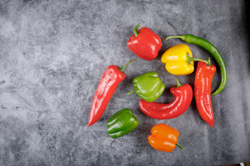 Mixed color bell peppers and chilies in the right side of the background. Top view.