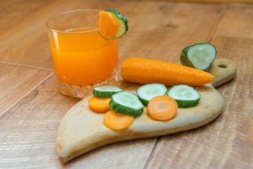 Carrot juice. Healthy food, healthy drink. Orange juice in a glass and next to peeled carrots, sliced cucumber.  healthy eating for breakfast. Wood background