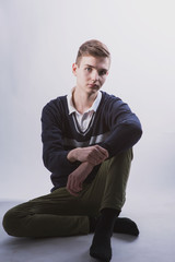 Lifestyle photo of a young brown-haired man on a light background, a beautiful young guy in a shirt and sweater