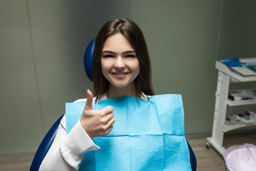 beautiful young smiling brunette patient woman having examination at dental office showing like sign, looking happy, healthcare concept
