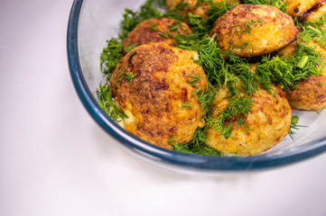 Meat cutlets with greens on a transparent dish on a light background