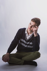 Lifestyle photo of a young brown-haired man on a light background, a beautiful young guy in a shirt and sweater