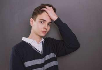 Lifestyle photo of a young brown-haired man on a light background, a beautiful young guy in a shirt and sweater