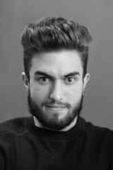 Close-up black and white portrait of a young handsome Caucasian male in studio. A man shows different human emotions.