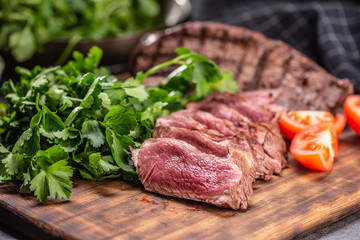 Slices of juicy grilled beef steak on a butcher plate